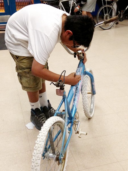 Ricardo Tovar, estudiante de séptimo grado en Safford Middle School, trabaja reparando una bicicleta el miércoles por la noche en el club de bicicletas en el Centro Juvenil John A. Valenzuela. (Foto por Hollie Dowdle.)