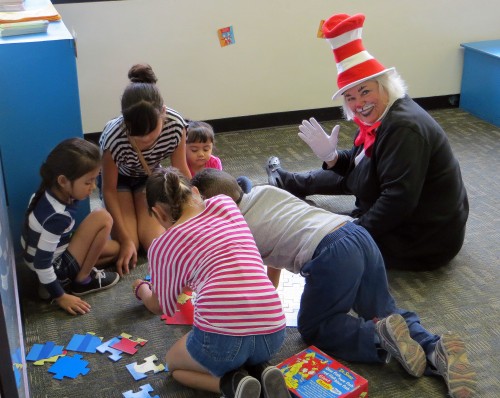 The Cat in the Hat, Kathy Bayer, puts together puzzles with children at El Rio Congress Clinic’s Reach out and Read event.  Photo by Caitlin Schmidt, El Independiente.