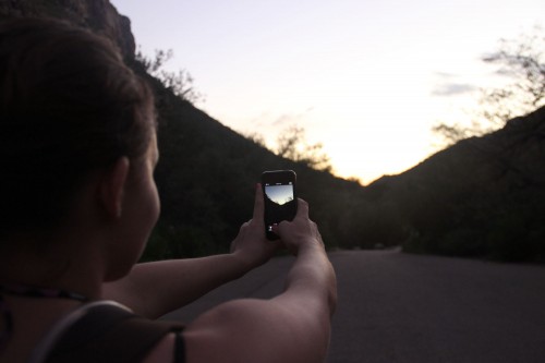 A hiker snaps a photo of a beautiful Arizona sunset during her hike at Sabino Canyon. Photo Illustration by Mark Armao. 