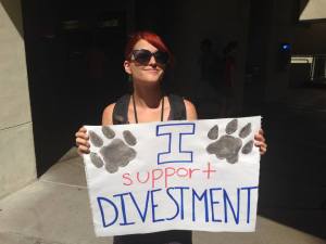 A UA student holds a sign to demonstrate student support for divestment. Photo courtesy of Divest UA.