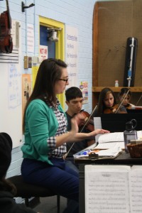 Margie Looney helps conduct her students while they play "Hoe Down" from Rodeo on March 23, 2015. Photograph by Alexandra Adamson 