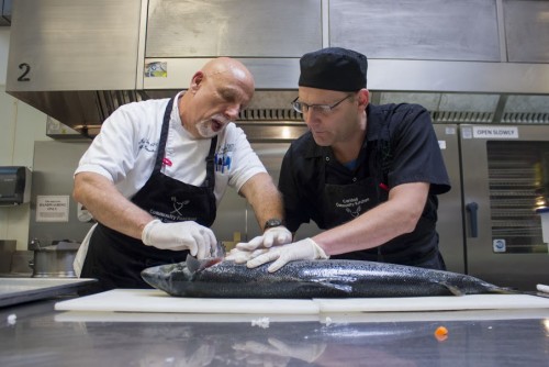 David Rogers (right), graduating student cook, and Jon Wirtis, executive chef and instructor, cut salmon for the graduation dinner at Caridad Community Kitchen, 845 N. Main Ave, on Friday, May 1, 2015. Students made dishes to match the Hawaiian theme of the graduation ceremony. Photo taken on Friday, May 1, 2015. Photo by Rebecca Marie Sasnett / Arizona Sonora News