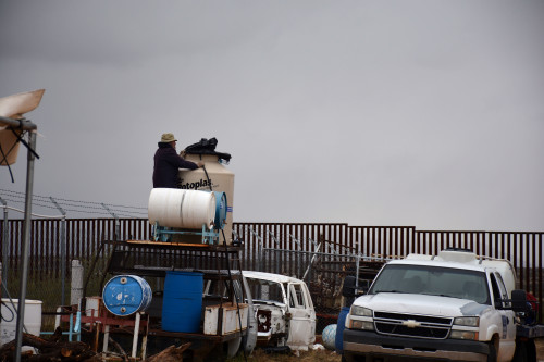 Humane Borders volunteer, John Hoelter, looks across the U.S. and Mexico border as he transfers water to tanks used by Grupo Beta in Sasabe, Sonora. The Mexican organization uses the water to provide aid to migrants near the border. Photo by Jorge Encinas/Arizona Sonora News.