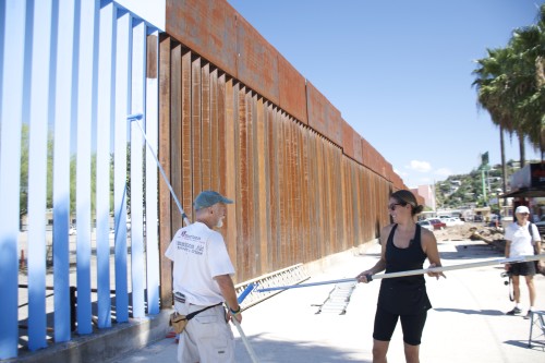 Activist Steve Teichner helps artist Ana Teresa Fernández paint the border wall in Nogales, Sonora. Photo by Kendal Blust