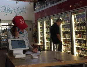 Rebecca Sofford (left) talks on the phone at the register inside Tap & Bottle, Tucson, Ariz. (Photo by Nick Peppe/ Tombstone Epitaph)