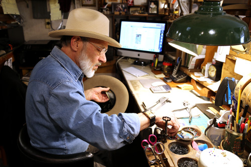 S. Grant Sergot, a Bisbee hatter, works on a customers fedora, installing an eyelet for the leather thong that keeps the hat on in the wind. Photo by Karen Schaffner/Arizona Sonora News Service