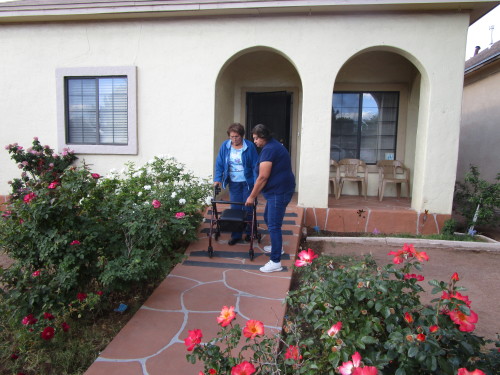 Rosa Buelna (right), 47, helps her mother Ysidra Buelna, 75, walk down the ramp outside of their house in Douglas, Arizona, to walk around the neighborhood. Rosa Buelna is her mother's caregiver. (Photo by Joanna Daya)