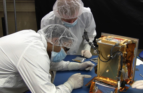MIT graduate students Pronoy Biswas (left) and Mark Chodas prepare the Regolith X-Ray Imaging Spectrometer (REXIS) instrument for flight. Photo by William Litant/MIT