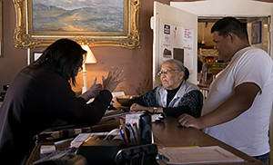 Edison Eskeets bargains with weaver Maggie Mannie over the two rugs she brought to sell to the Hubbell Trading Post National Site in Ganado. The bargaining was done in Navajo.