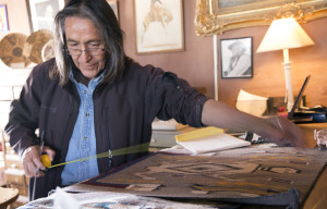 Edison Eskeets measures one of the rugs a local weaver has brought to sell to Hubbell Trading Post National Site. Eskeets is the post’s trader.