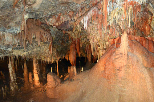 Large flowstone with bold red and pink colors due to iron being brought in with the water from the overlaying rock in the strawberry room in Kartchner Caverns State Park. Due to the abundant amounts of iron in this area, the discoverers were inspired to called this the Strawberry Room. (Photo courtesy of Kartchner Caverns State Park)