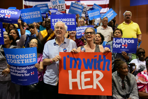 Jeff Fisher, left, and Diana Vangellow, right, hold a sign together before First Lady Michelle Obama's speech at the Phoenix Convention Center in Phoenix, Ariz. on Thursday, Oct. 20, 2016. "I think it's wonderful to have a woman as the President, but that's not the key issue," said Fisher. "It is critical that we have the proper leadership in the world and we just want to make sure the most qualified person is able to lead our nation." (Photo by Rebecca Noble / Arizona Sonora News)