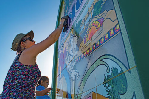 Anna Aguilar, a resident of South Tucson, cleans the mural at 4th Avenue near Benson Highway on Saturday, Sept. 24, 2016. Aguilar participates in a clean-up, part of a larger beautification project organized by the Healthy South Tucson coaltion.