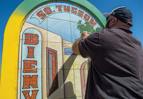 Lorenzo Gonzalez, South Tucson city planner, removes tape from a newly painted mural at 4th Avenue near Benson Highway on Sept. 24, 2016. As president of the Healthy South Tucson coalition, Gonzalez hopes painting the murals will bring greater pride to the citizens of South Tucson.