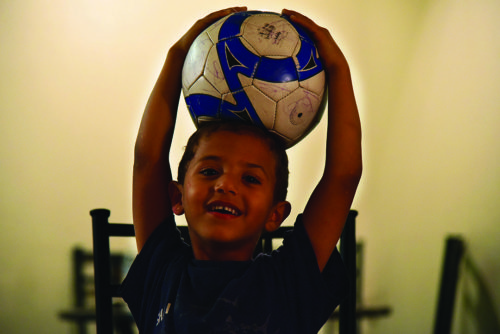 Mahmoud Al-Rahmoon plays with his only toy, a slightly deflated soccer ball, in his familys apartment on Oct. 16, 2016. Al-Rahmoon dreams of one day owning his own car and airplane and becoming a professional soccer player. (Photo by Rebecca Noble / Arizona Sonora News)