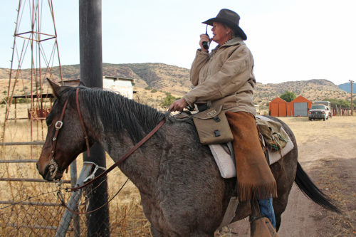 Kelly Glenn Kimbro radios the rest of the team working the cattle round at the Glenns J Bar A Ranch up on Saturday, Nov. 25, 2016.  With everyone spread out throughout the ranch land, they communicate by walkie talkies to get all the cattle together. (Photo by Michelle Floyd / Arizona Sonora News)
