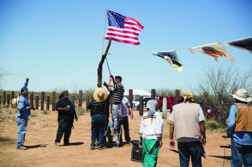 Tohono O’odham members and other southern tribe members hang a flag at the U.S.-Mexico border. Photo by Alejandaro Higuera.