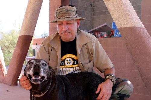 Harry Hughes pets his dog, Bailey, in a ramada near the town of Maricopa, Ariz. When not operating as the press arm of the National Socialist Movement, Hughes is an amateur photographer. Photo by: Erik Kolsrud/Arizona Sonora News