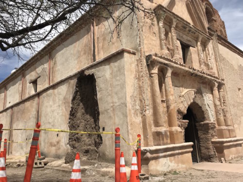 Cones encircle a hole on the side of the San Jose de Tumacacori church. The hole is a result of heavy rainstorms in February, where water got under the structures plaster layer and got to the adobe underneath. (Photo by Ava Garcia/Arizona Sonora News Service)