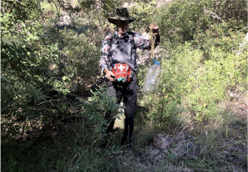 Brian Best, Tucson Samaritans member, recovers a water jug from the bushes in a canyon of Peña Blanca in Coronado National Forest. Photo: MacKenzie Carolan | El Inde.