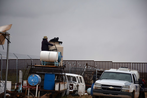 John Hoelfer, un voluntario de Humane Borders, una organización humanitaria no lucrativa, mira hacia el otro lado de la frontera entre México y Estados Unidos mientras pone agua en los tanques que se usan por el Grupo Beta en Sásabe, Sonora. La organización mexicana tiene localidades a lo largo de la frontera para ofrecer ayuda a los migrantes. (Fotografía por Jorge Encinas /  Arizona Sonora News Service)