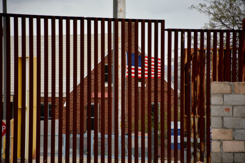 La bandera estadounidense entre el muro fronterizo en Sásabe, Sonora. La estación estadounidense de aduanas se encuentra directamente al otro lado de los tanques del Grupo Beta. (Fotografía por Jorge Encinas / Arizona Sonora News)