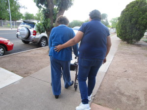 Rosa Buelna (right) holds her mother's back for support while walking. Buelna walks with her mother around their Douglas, Arizona, neighborhood as a form of exercise. (Photo by Joanna Daya)