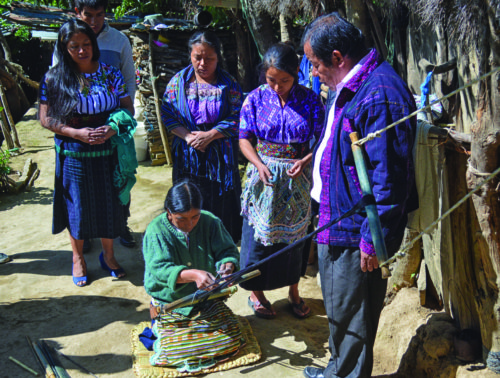 Mayor Manuel Tahay speaks with women weaving in Nahuala, Guatemala on July 24, 2016. Emigration to the U.S. has left few men in the town. (Photo by Emily Ellis)