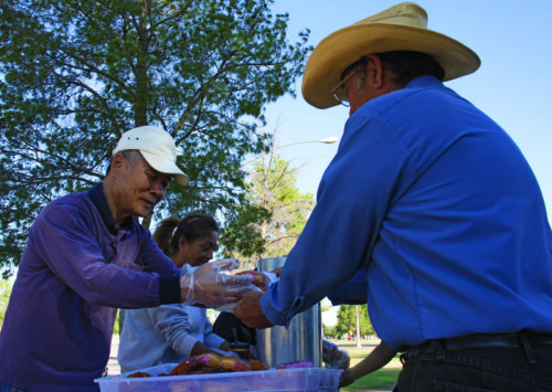 Jay Kim, a member of The Loving Church, hands a donut to a homeless man at Santa Rita Park in South Tucson, Ariz. on Thursday, Nov. 3, 2016. The members of the church feed the homeless Tuesday through Saturday. (Photo by Michael Evans)