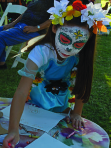 Emma Nelms, 8, write a message for their deceased family members at the Little Angels Procession at Armory Park Center on Saturday, November 5. Photo by: Christina Duran