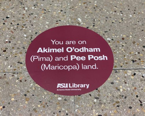 A red sticker on the ASU Library floor reads, "You are on Akimel O'odham (Pima) and Pee Posh (Maricopa) land."