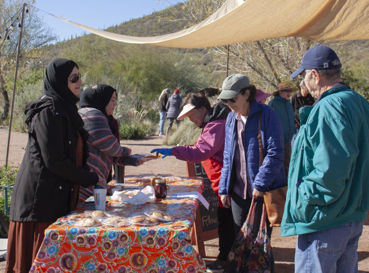 Afaf Hasan talks to a visitor while selling homemade citrus sweets at the Mission Garden in Tucson, Ariz. on Feb. 9, 2024. ELFA collaborated with the Mission Garden to table at its “Tasting History” event.