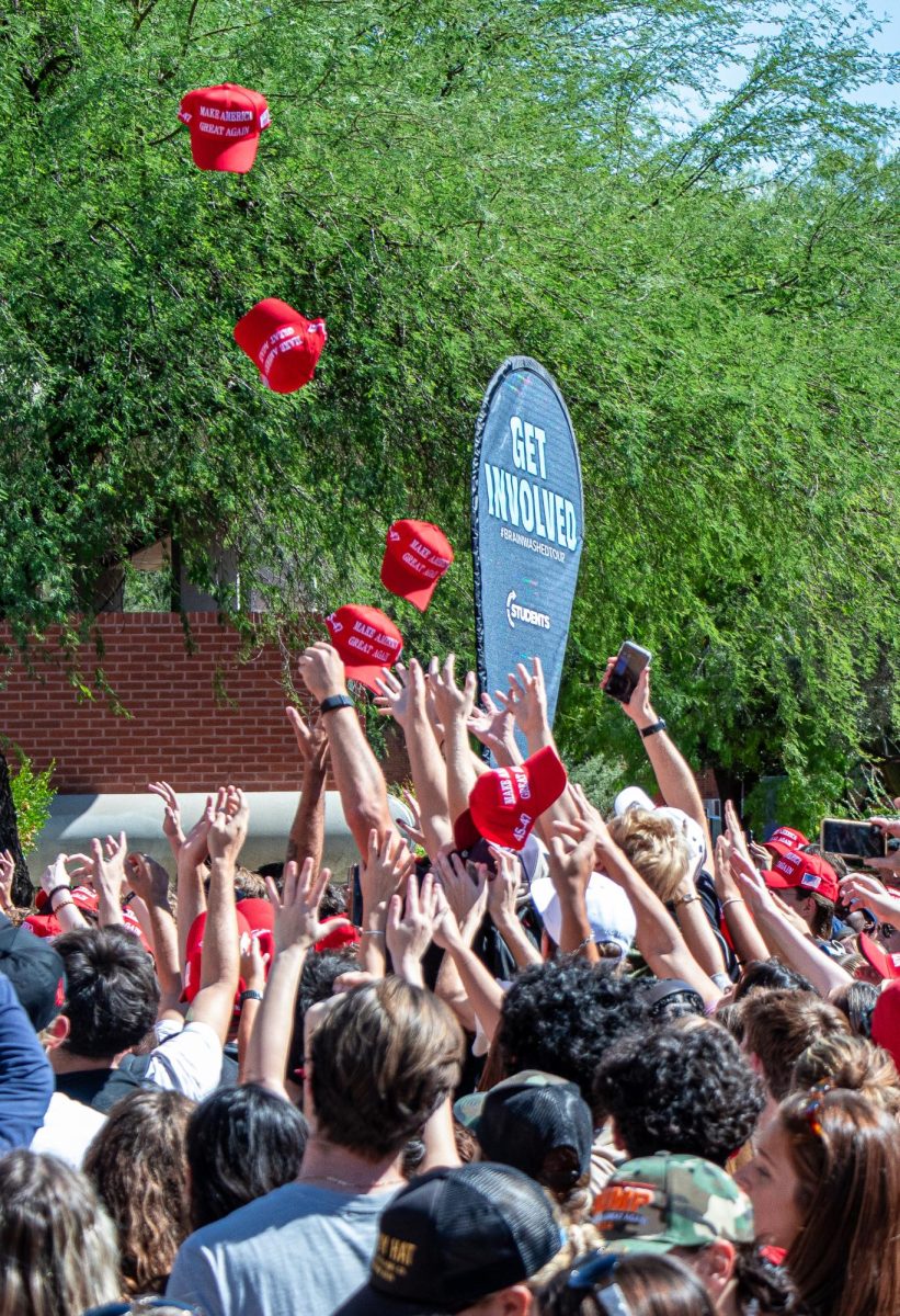 Students reach for MAGA hats thrwn from Charlie Kirk a well known republican and political influencer cam to the University of Arizona campus on Oct. 16.