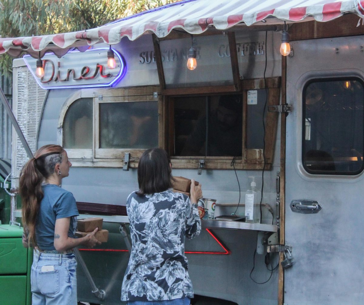 Two people pick up a takeout order at Substance Diner on Tuesday, Oct. 15. Substance Diner is a vegan food truck.