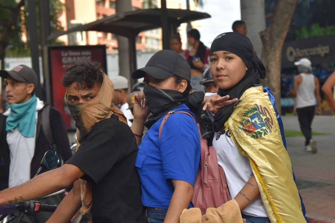 Three protesters ride a motorcycle on Avenue Libertador in Chacao on July 29, following the Venezuelan presidential elections. That day, residents from the poorest neighborhoods, including Petare—a former socialist stronghold, the biggest favela of Latin America—poured into the streets of Caracas to denounce electoral fraud. The avenue, a key artery connecting eastern Caracas, became a focal point for demonstrations and repression, as disillusionment spread from the working-class barrios to the city's urban core. 