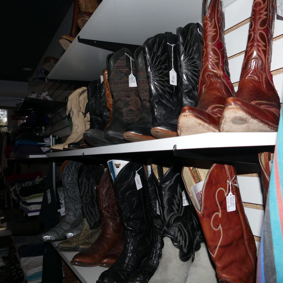 Cowboy boots from the 80s and 90s showcased towards the back of the store on shelves. 