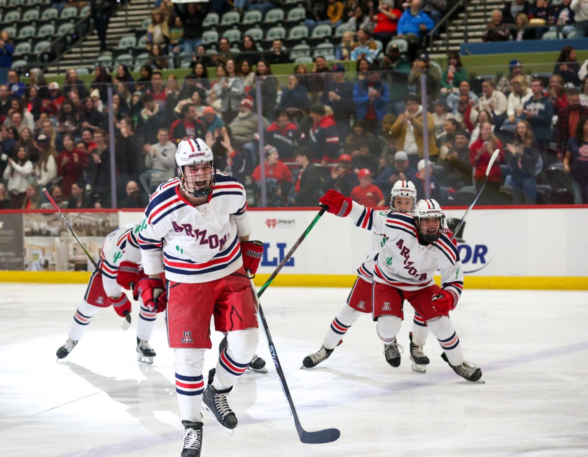 Forward Justin Hughes, left, cheers after scoring against ASU in the first game of the Cactus Cup in Tucson Arena on Dec. 5. The Wildcats won that matchup 4-1. 