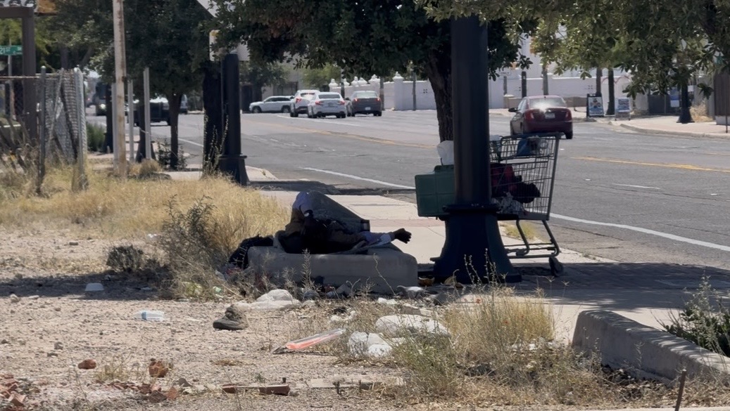 A homeless individual finds relief beneath a shade tree in a Tucson park. Tucson area cooling centers opened early after a heatwave in March led to three heat-related deaths.  